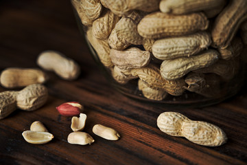 Close up of peanuts in a jar on rustic wooden background