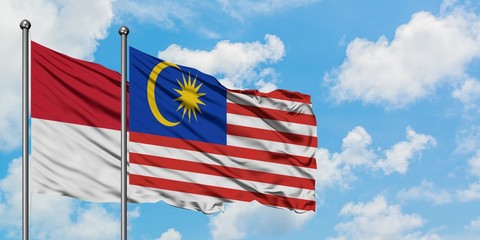 Iraq and Malaysia flag waving in the wind against white cloudy blue sky together. Diplomacy concept, international relations.