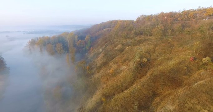 Aerial view of river under morning fog and golden hills, Ukraine