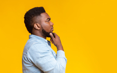 Profile portrait of thoughtful african american guy over yellow background
