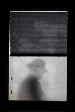 Man wearing hat behind glass window
