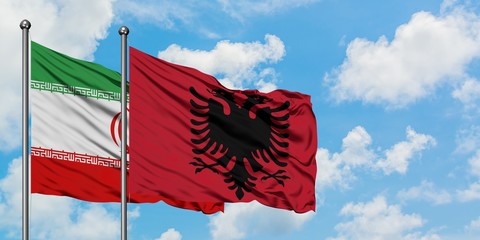 Iran and Albania flag waving in the wind against white cloudy blue sky together. Diplomacy concept, international relations.
