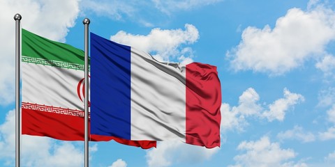 Iran and France flag waving in the wind against white cloudy blue sky together. Diplomacy concept, international relations.