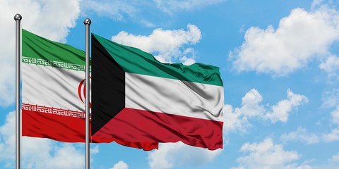 Iran and Kuwait flag waving in the wind against white cloudy blue sky together. Diplomacy concept, international relations.