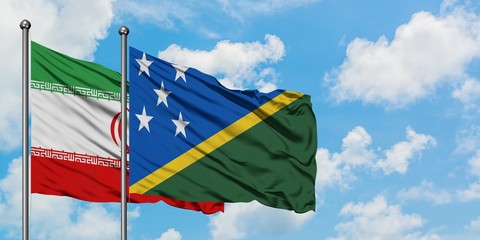 Iran and Solomon Islands flag waving in the wind against white cloudy blue sky together. Diplomacy concept, international relations.