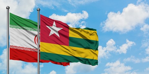 Iran and Togo flag waving in the wind against white cloudy blue sky together. Diplomacy concept, international relations.