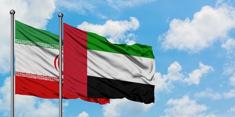 Iran and United Arab Emirates flag waving in the wind against white cloudy blue sky together. Diplomacy concept, international relations.