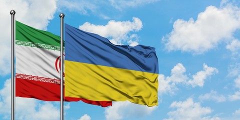 Iran and Ukraine flag waving in the wind against white cloudy blue sky together. Diplomacy concept, international relations.