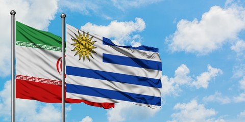 Iran and Uruguay flag waving in the wind against white cloudy blue sky together. Diplomacy concept, international relations.