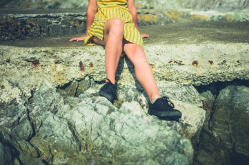 Young woman relaxing on rocks by the sea