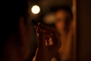 Sensual woman applying makeup in romantic light, evening out