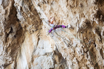 Young woman climbing challenging route on overhanging cliff