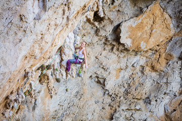 Young female climber resting while sitting on calanet. Woman climber smiling and looking at camera.