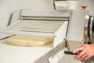 pastry cook using a rolling mill to prepare a puff pastry