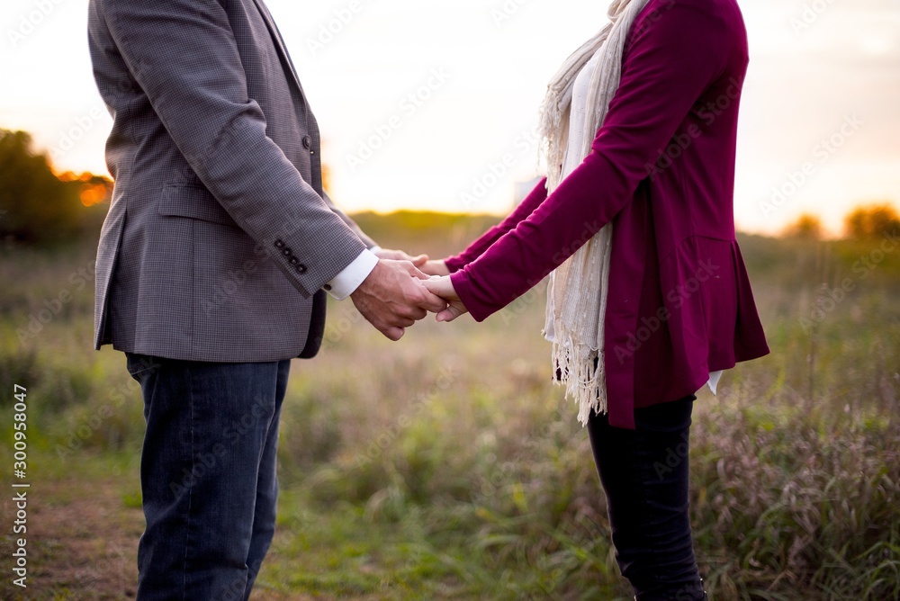 Poster closeup shot of a couple holding hands with a blurred natural background