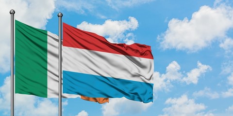 Ireland and Luxembourg flag waving in the wind against white cloudy blue sky together. Diplomacy concept, international relations.