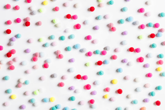 Texture of small colorful textile fluffy pompons on a white background. Flat lay. Creative.