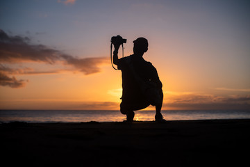 The silhouette of a male hobbyist photographer taking photos of a beautiful colorful sunset on the West Puerto Rico coast near Rincon