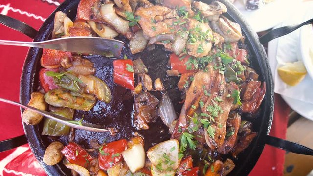 Traditional Bulgarian Kavarma - stewed marinaded meat with vegetables and mushrooms with greens in restaurant