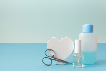 Manicure tool set. Blue nail lacquer remover, transparent nail polish and scissors on blue...