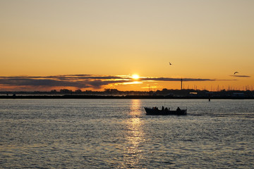 A fishing boat leaving the harbour during sunrise in Warnemünde