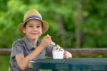 happy boy eating ice cream on the street cafe. portrait of child enjoying the dessert outside