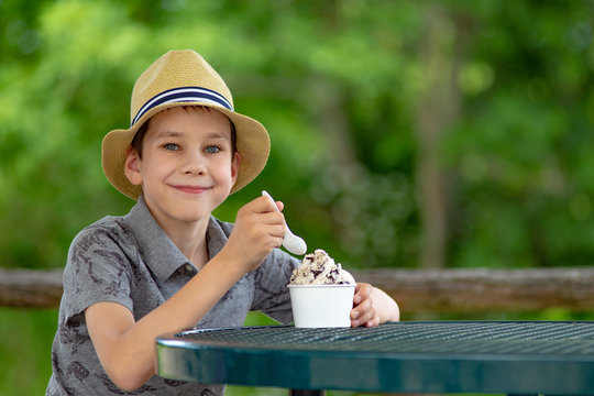 happy boy eating ice cream on the street cafe.  portrait of child enjoying the dessert outside