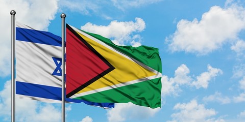 Israel and Guyana flag waving in the wind against white cloudy blue sky together. Diplomacy...