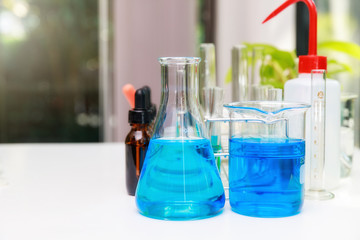 Blue experiment water in beaker and flask in chemistry science laboratory. Group of laboratory flasks with liquid inside.