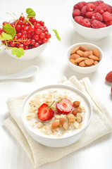 Oatmeal porridge with strawberry slices and nuts in bowl