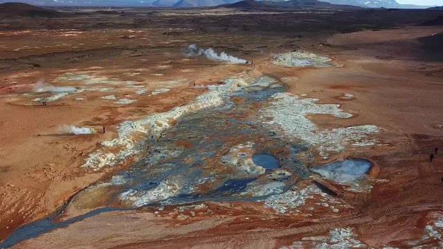 Aerial, orbit, drone shot, overlooking the Hverir geothermal area, full of smoking craters emitting sulfuric gas, on a sunny, summer day, in North Iceland