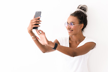 Smiling positive young african woman with dreads posing isolated over white wall background take...