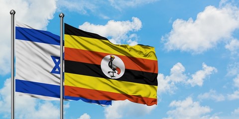 Israel and Uganda flag waving in the wind against white cloudy blue sky together. Diplomacy concept, international relations.