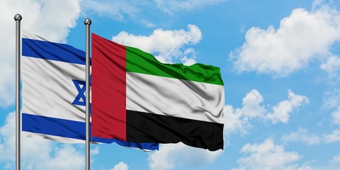 Israel and United Arab Emirates flag waving in the wind against white cloudy blue sky together. Diplomacy concept, international relations.