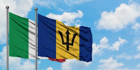 Italy and Barbados flag waving in the wind against white cloudy blue sky together. Diplomacy...
