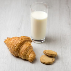 A croissant, some cookies and a glass of milk