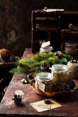 homemade liver pate in glass jars on rustic table with fir tree branches, toys