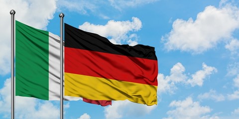 Italy and Germany flag waving in the wind against white cloudy blue sky together. Diplomacy concept, international relations.