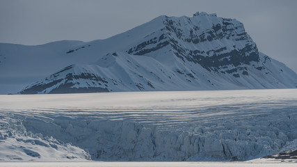 Cracking glacier with crevasses in the ice and mountains in the background