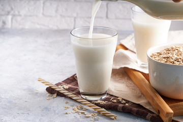 Healthy alternative milk. Homemade oat milk in glass and bottle on light table Lactose free
