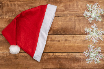 Obraz na płótnie Canvas Santa hat and snowflakes on a wooden background.