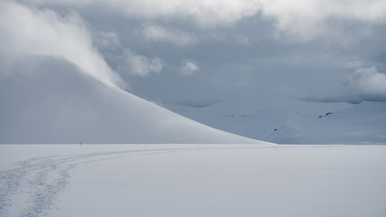 Fototapeta na wymiar Snowy mountain landscape in the arctic with tracks in the front