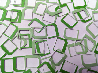 A lot of green plastic SIM frames lying on a white background, texture