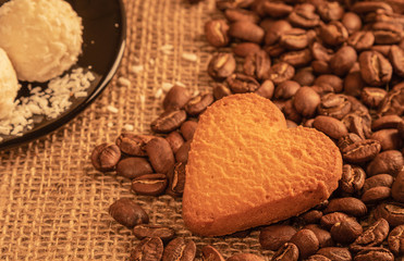  top view on heart cookies on coffee beans on the background of burlap and other sweets