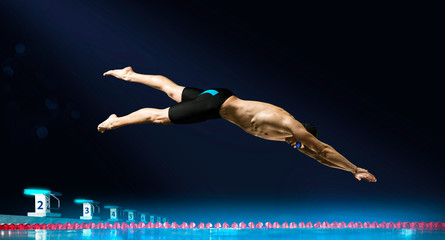 Swimmer jumping from starting block in a swimming pool