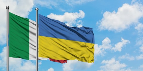Italy and Ukraine flag waving in the wind against white cloudy blue sky together. Diplomacy concept, international relations.