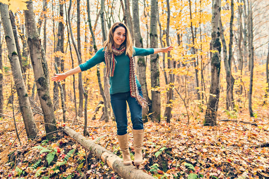 a woman crossing a tree on the forest in autumn - Powered by Adobe