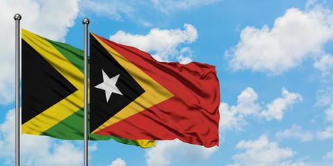 Jamaica and East Timor flag waving in the wind against white cloudy blue sky together. Diplomacy concept, international relations.