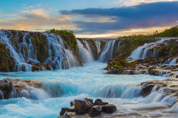 Majestic summer sunrise on Bruarfoss Waterfall. The 'Iceland’s Bluest Waterfall.' Blue water flows over stones. Midnight sun of Iceland. Visit Iceland. Beauty world.