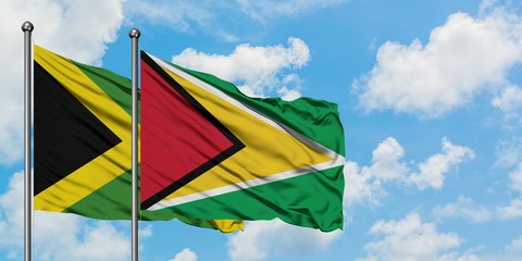 Jamaica and Guyana flag waving in the wind against white cloudy blue sky together. Diplomacy concept, international relations.